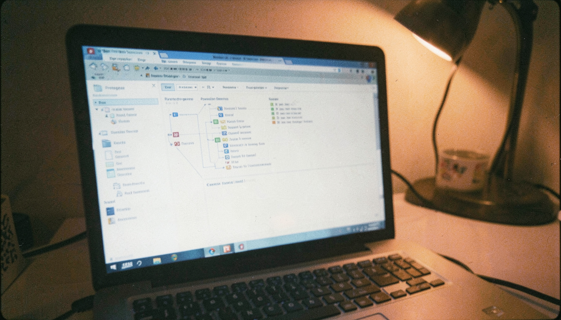 An analog film photograph with subtle grain showing a close-up of a laptop screen displaying a Protégé ontology editor interface with class hierarchies and property panels visible.